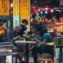 People eating in outdoor street food restaurant in Hong Kong at night